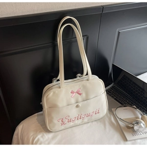 Detail of cream white tote bag featuring pink bow decoration and custom embroidery text