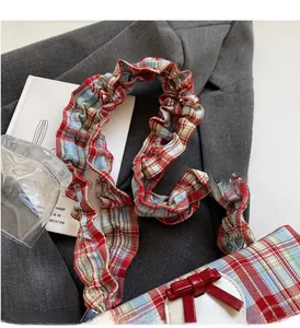 Detail of red and blue plaid handbag with ruffled strap and red 3D bow decoration