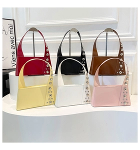 Detailed row of punk style patent leather tote bags with rivets in multiple colors