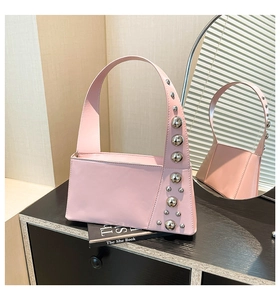 Detail of pink leather handbag showing silver sphere rivets and sleek shoulder strap design
