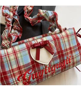 Detail of tartan canvas tote with heart patch, red bow, and cursive embroidery