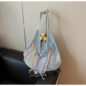 Close-up of light blue hollow knit tote bag with colorful decorative braided cords