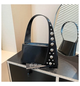 Close-up of a glossy black leather underarm bag with stylish silver metal stud accents