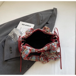 Detail of red and blue checkered tote bag featuring ruffle trim and silk bow ties