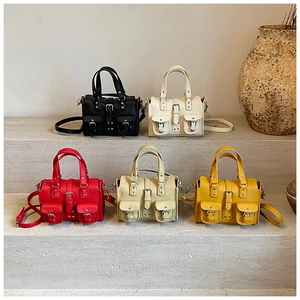 Detailed view of women's leather handbags in multiple colors arranged on stone steps