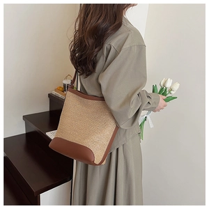 Detail of handwoven straw tote bag with brown leather trim and shoulder strap for women
