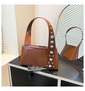 Detailed view of brown glossy leather bag featuring silver metallic stud decorations