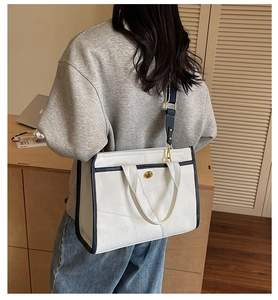 Détail du sac cabas en toile blanc avec bordure bleu marine et fermoir doré chic