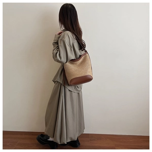 Large straw tote bag with brown leather trim shown from a side view on a model