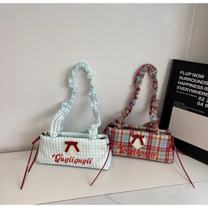 Detail of plaid baguette bags featuring heart patches, red bows and ruffled cloud handles