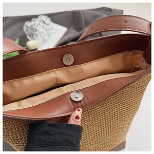 Detail of straw tote bag showing brown leather trim and metal magnetic closure