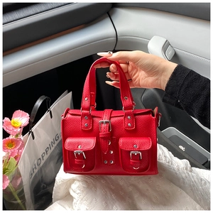 Close-up of red litchi texture leather handbag with vintage buckle pockets in car setting