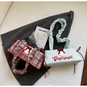 Detail of checkered and striped canvas tote bags featuring ruffled handles and heart embroidery