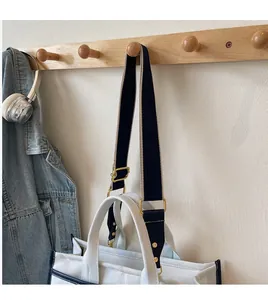 Detail des abnehmbaren blauen Gurtes und der goldenen Metallhaken an der Denim-Tasche