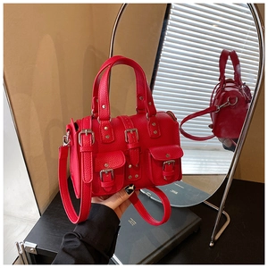 Detail of red textured leather motorcycle bag with silver metal buckles and mirror reflection