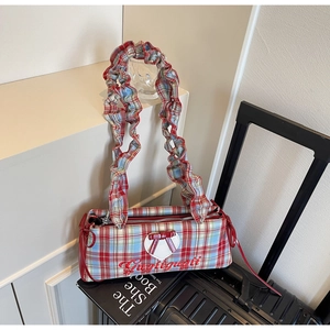 Macro view of British plaid fabric with red bow and heart patch on a pleated shoulder bag