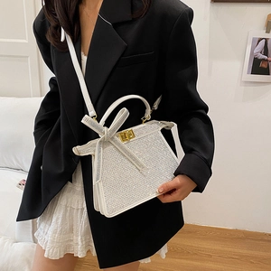 Sac à main blanc à strass avec nœud et fermoir doré porté avec une bandoulière
