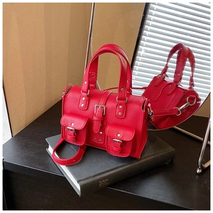 Detailed close-up of red lychee pattern leather handbag with silver studs and dual pockets
