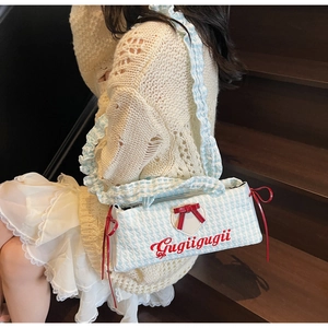 Detail of blue gingham shoulder bag with red bow and ruffled strap on a model