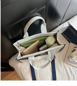 Draufsicht auf den geräumigen Innenraum der cremefarbenen Segeltuchtasche mit Büchern