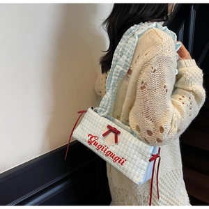 Detail of blue and white checkered canvas tote bag with red bow and Gugu embroidery