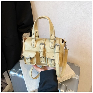 Detail of yellow pebbled PU leather handbag featuring triple front buckle pockets and silver hardware
