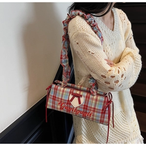 Detail view of red plaid canvas tote bag featuring ruffled shoulder strap and bow accents
