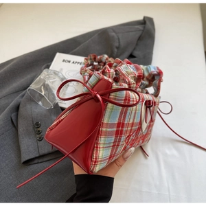 Detail of red plaid canvas bag with shiny leather trim and bow knot decoration