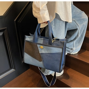 Détail du sac cabas en denim patchwork avec fermoir doré en métal et surpiqûres blanches