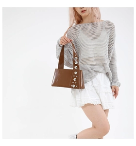 Brown glossy handbag with large silver rivets shown on model for a trendy summer look