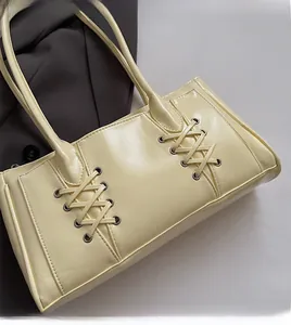 Détail du sac beige avec œillets argentés et design de laçage croisé sur le devant