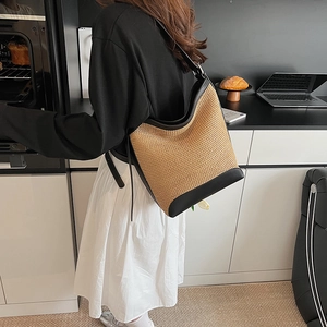 Large straw bucket tote bag with black leather trim and adjustable shoulder strap