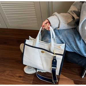 Détail d'un sac cabas bicolore avec fermoir rotatif doré et bandoulière large