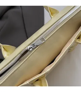 Gros plan sur la fermeture éclair en métal argenté du sac à main jaune pâle en similicuir