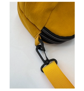 Détail du sac à bandoulière en nylon jaune avec fermetures noires et crochets robustes