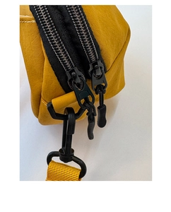 Détail du sac coquillage jaune montrant les fermetures éclair et la bandoulière