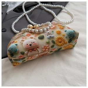 Close-up of bear embroidery and pearl handle detail on a chic cream crossbody bag