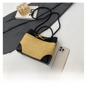 Detailed shot of woven straw handbag with black leather trim and golden knot buckle