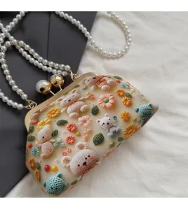 Detail of floral and bear 3D embroidery on beige shell bag with pearl handles