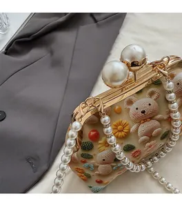 Detail of vintage cream bag with crochet bear, pearl chain, and gold metal clasp