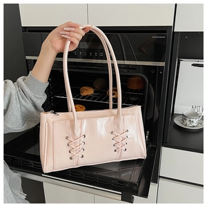 Détail du sac baguette en cuir verni rose avec lacets et œillets métalliques argentés