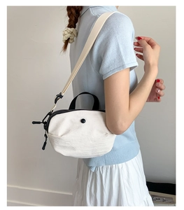 Détail du petit sac bandoulière en toile blanche avec poignée noire et boucle ronde