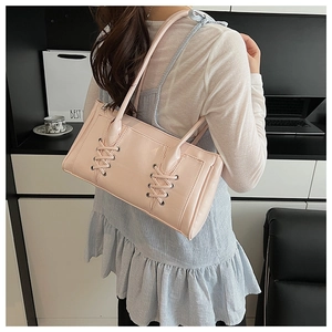 Détail du sac sous le bras en cuir verni rose avec lacets croisés et œillets métalliques