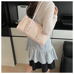 Vue détaillée du sac cabas en cuir verni rose avec lacets porté par un mannequin