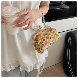 Detail of beaded pearls strap and crochet floral bear design on crossbody bag