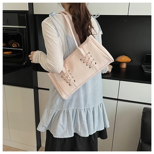 Sac sous le bras en similicuir rose avec lacets décoratifs croisés dans un décor de cuisine