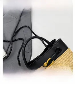 Close-up of straw and black leather handbag with a golden knot buckle on grey blazer
