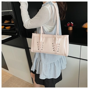 Gros plan d'un sac à épaule en cuir verni rose avec détails de laçage décoratifs