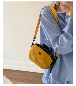 Vue détaillée du sac à bandoulière en nylon jaune moutarde porté par un mannequin sur une chemise