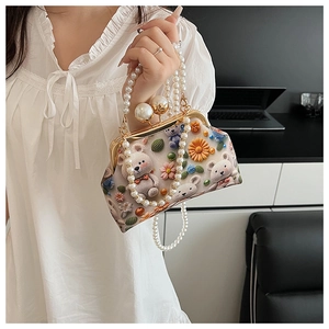 Detail of beaded shell bag with 3D crochet bear and pearl chain handle in beige